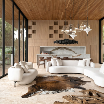 Mocha, chocolate and ivory cowhide rug styled on the floor of a bright modern loft living room