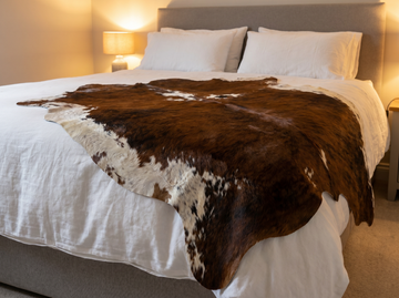 Brindle cowhide draped over bed as luxury throw