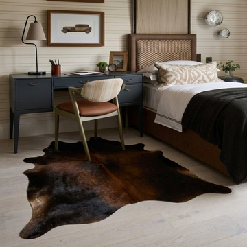 Caramel and ivory exotic printed cowhide rug styled on the floor of an editorial interior