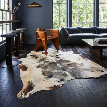 Caramel and ivory exotic printed cowhide rug styled on the floor of an editorial interior
