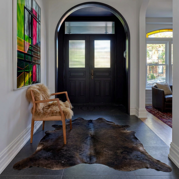 Natural cowhide rug styled on the floor of an editorial interior room