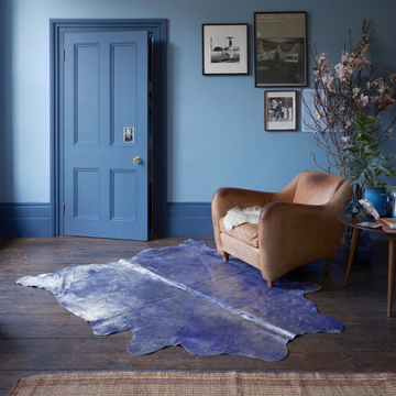 Violet metallic cowhide rug styled on dark timber boards in a blue-walled period sitting room
