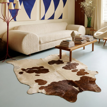 Caramel and ivory exotic printed cowhide rug styled on the floor of an editorial interior