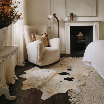 Caramel and ivory exotic printed cowhide rug styled on the floor of an editorial interior