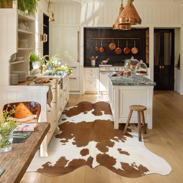 Brown and white natural cowhide rug styled on the floor of a cream and copper country kitchen