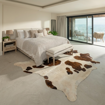 Caramel and ivory exotic printed cowhide rug styled on the floor of an editorial interior