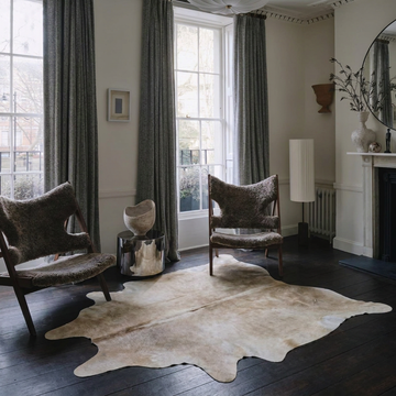 Caramel and ivory exotic printed cowhide rug styled on the floor of an editorial interior
