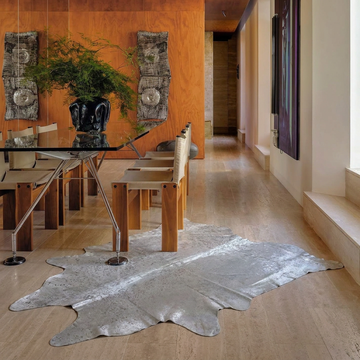 Silver on off-white metallic cowhide rug styled on the travertine floor of a contemporary dining hall