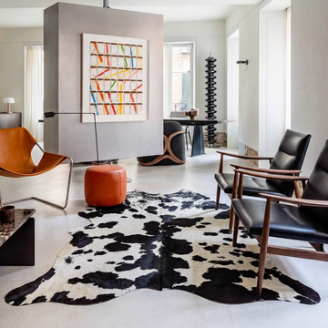 Black and white cowhide rug styled on the pale stone floor of a contemporary minimal living room
