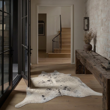 Caramel and ivory exotic printed cowhide rug styled on the floor of an editorial interior