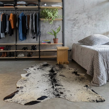 Black salt and pepper cowhide rug styled on the polished concrete floor of an industrial loft bedroom