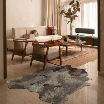 Distressed brown and grey acid-wash cowhide rug styled on the marble floor of a warm contemporary lounge