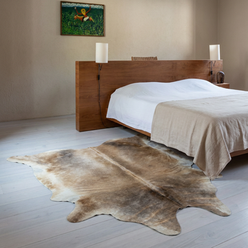 Caramel and ivory exotic printed cowhide rug styled on the floor of an editorial interior