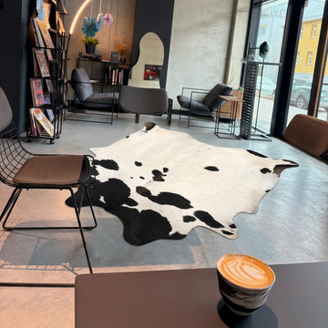 Caramel and ivory exotic printed cowhide rug styled on the floor of an editorial interior