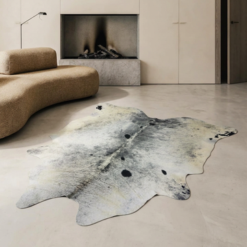 Salt and pepper grey cowhide rug styled on the concrete floor of a cool minimal living room