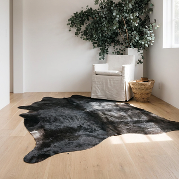 Caramel and ivory exotic printed cowhide rug styled on the floor of an editorial interior