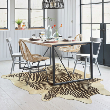 Zebra printed cowhide rug styled on the floor of a bright Scandinavian dining room
