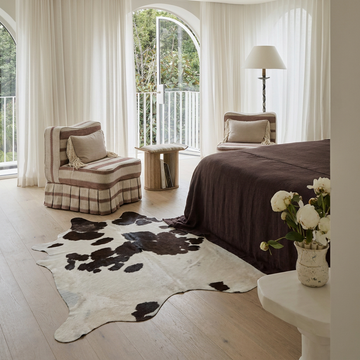 Caramel and ivory exotic printed cowhide rug styled on the floor of an editorial interior