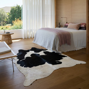 Black and white Holstein cowhide rug styled on the floor of an editorial interior