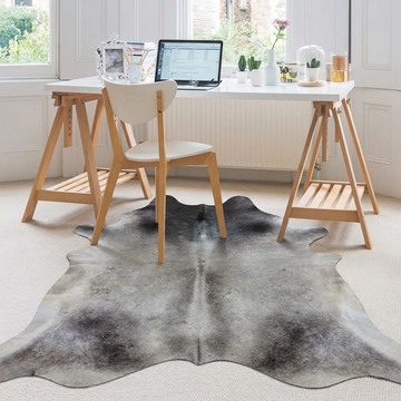 Grey cowhide rug styled under a trestle desk in a bright Scandinavian home office