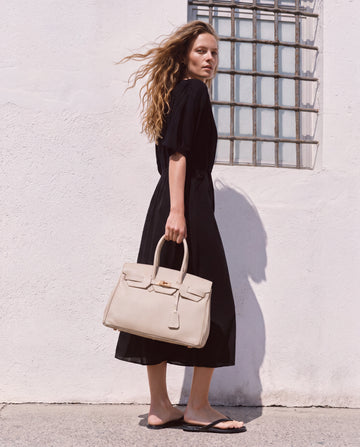 Woman by a whitewashed Mediterranean wall carrying the Oyster Valentina Maxi Leather Tote