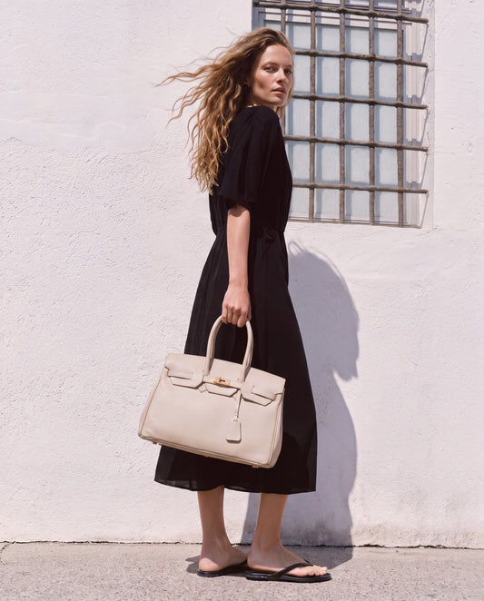 Woman by a whitewashed Mediterranean wall carrying the Oyster Valentina Maxi Leather Tote