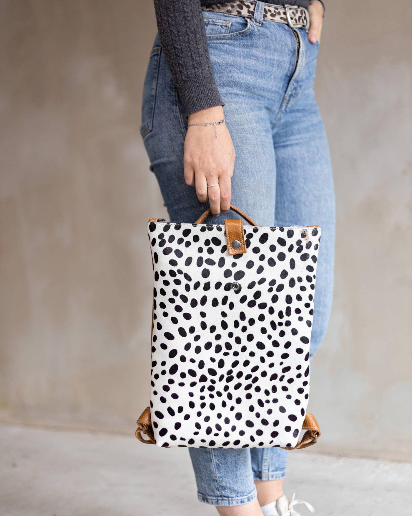 Woman holding the Dalmatian print Sandra backpack over jeans