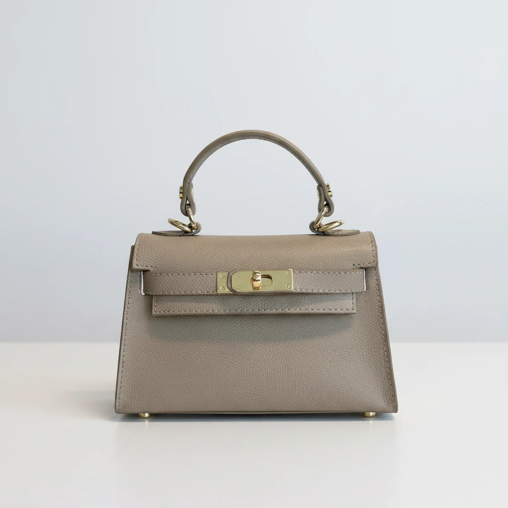 The Mini Kelly-Inspired Epsom Leather Handbag by Clemés in Light Taupe, three-quarter studio shot on grey background
