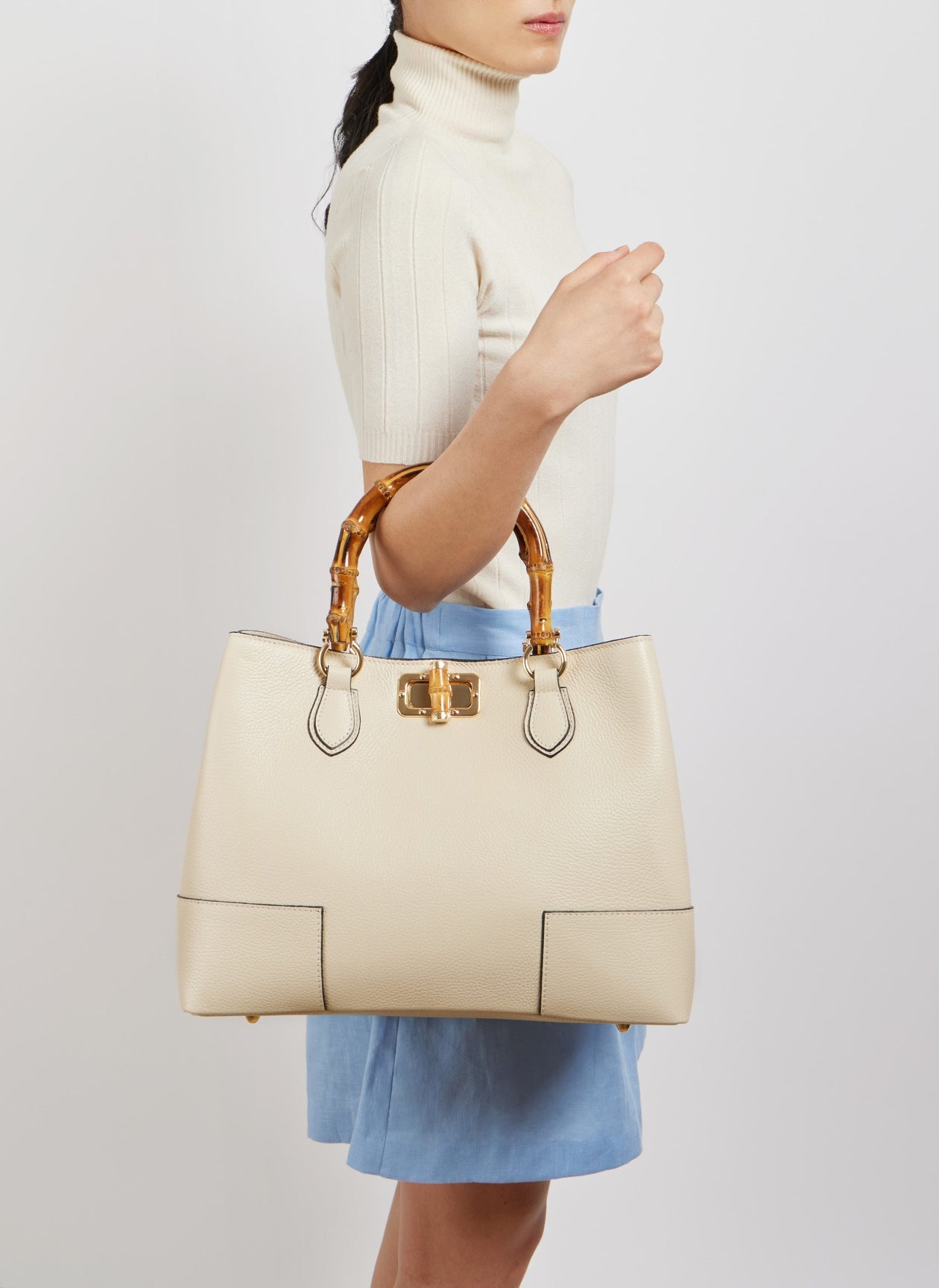 Woman carrying the White Ginevra Bamboo-Handle bag by its two handles
