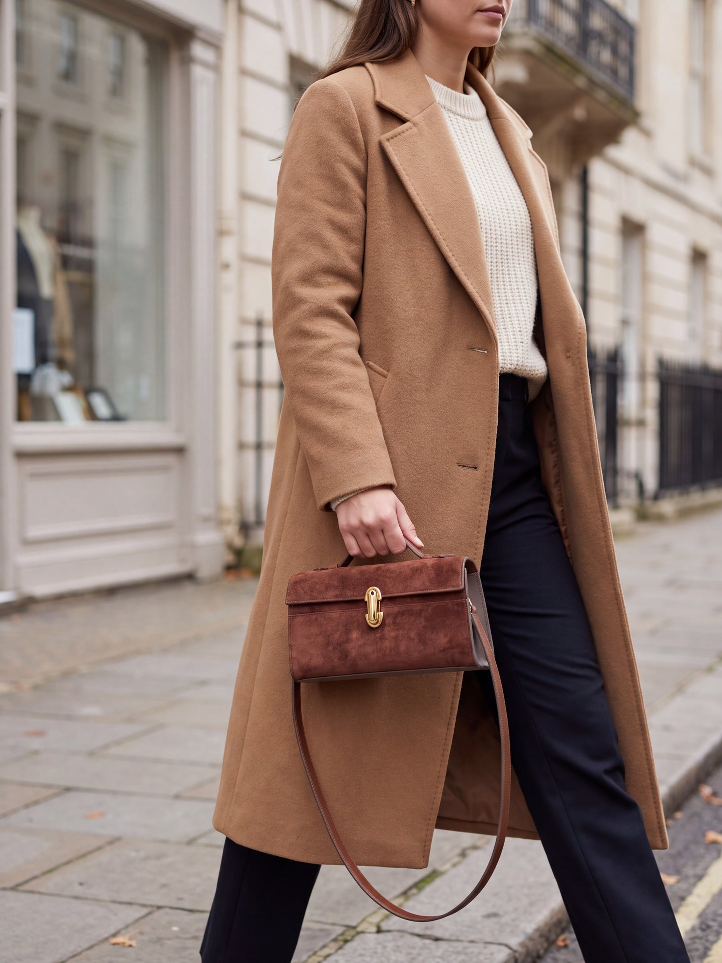 Woman walking a city street carrying the Tan Aurélie Suede Leather Baguette Bag by Clemés by its top handle