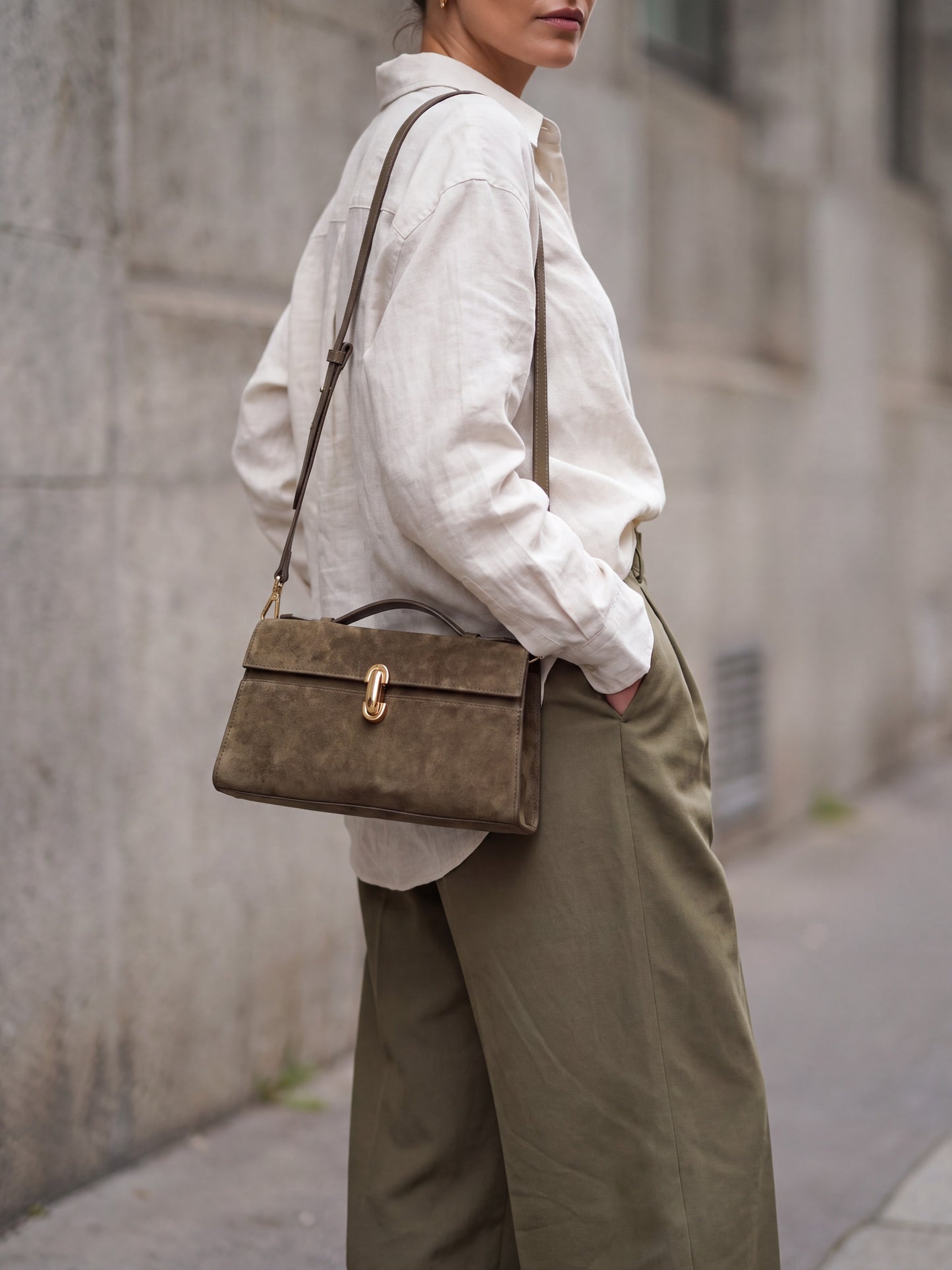 Woman wearing the Taupe Aurélie Suede Leather Baguette Bag by Clemés on the shoulder by its long strap