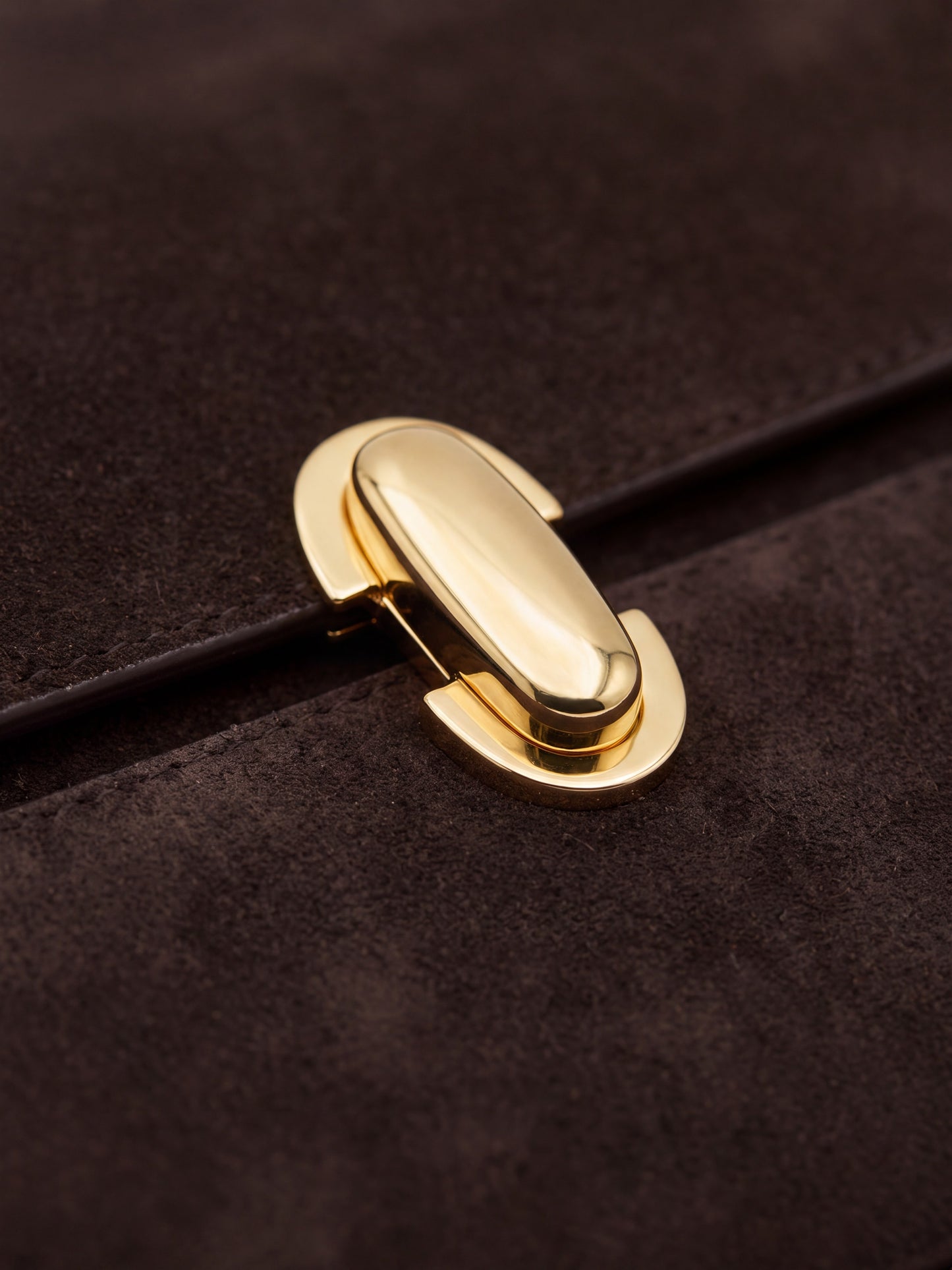 Gold turn-lock clasp detail on the Aurélie Suede Leather Baguette Bag by Clemés