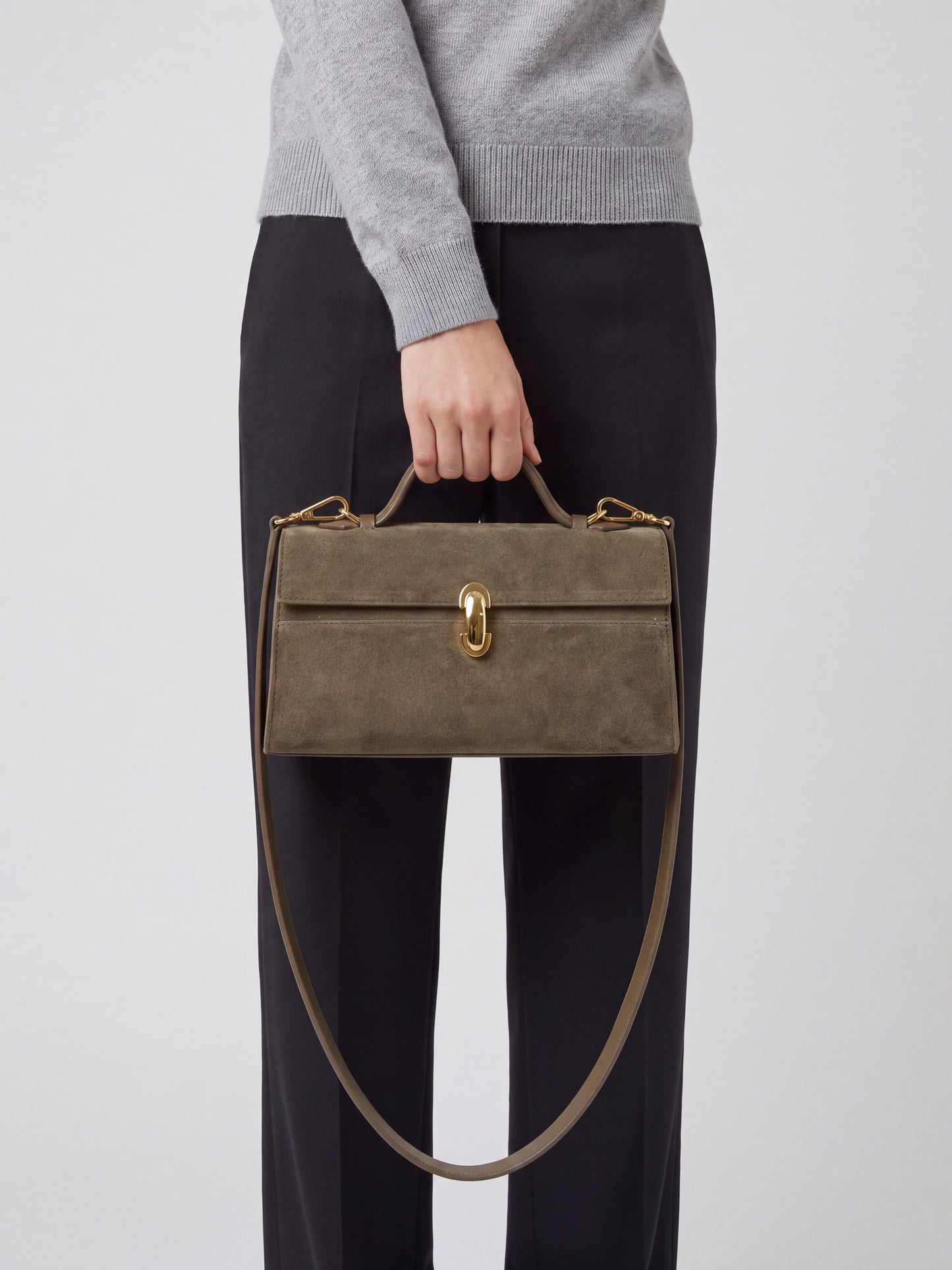 Model carrying the Taupe Aurélie Suede Leather Baguette Bag by Clemés by its top handle