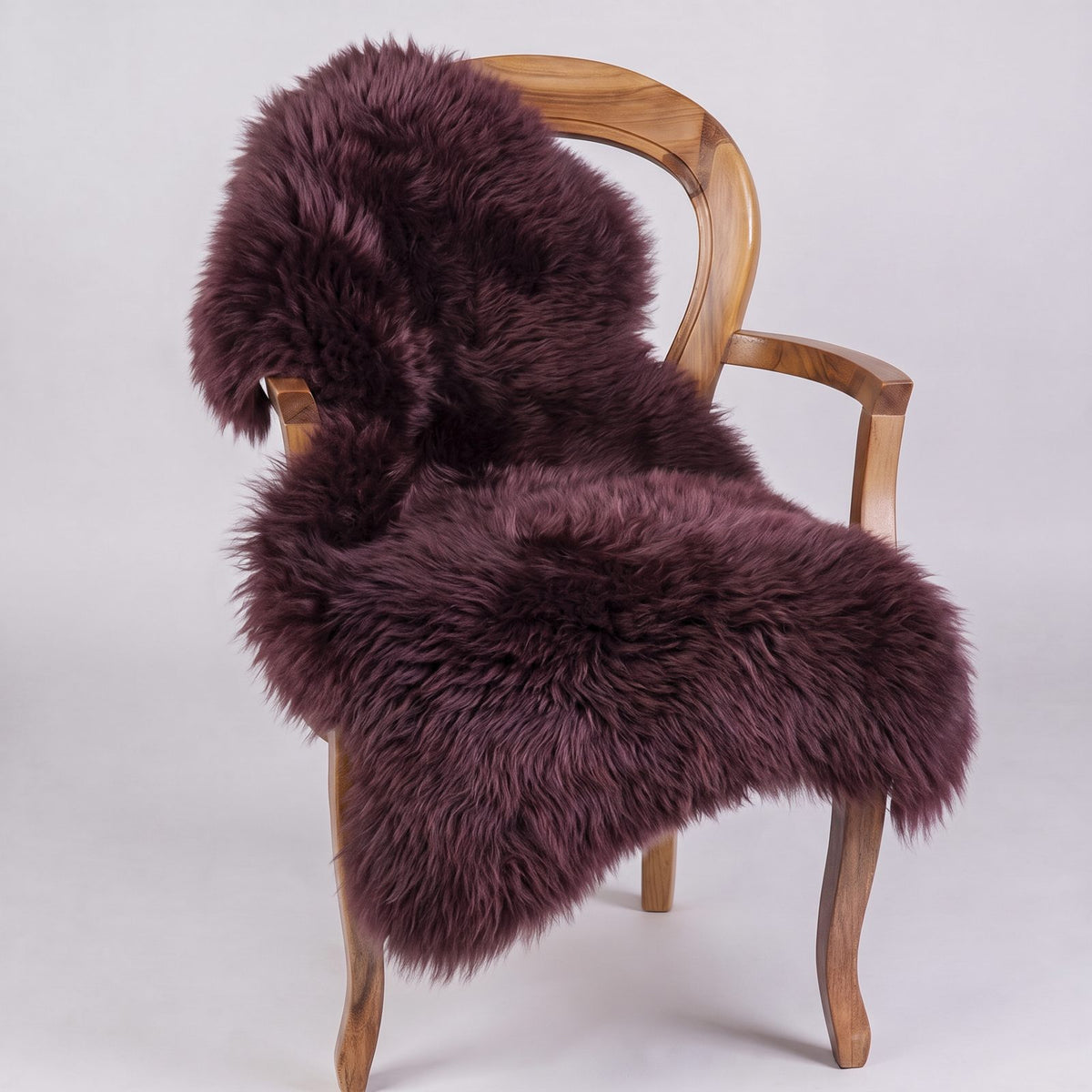 Aubergine New Zealand sheepskin throw draped over a wooden armchair, deep plum wool