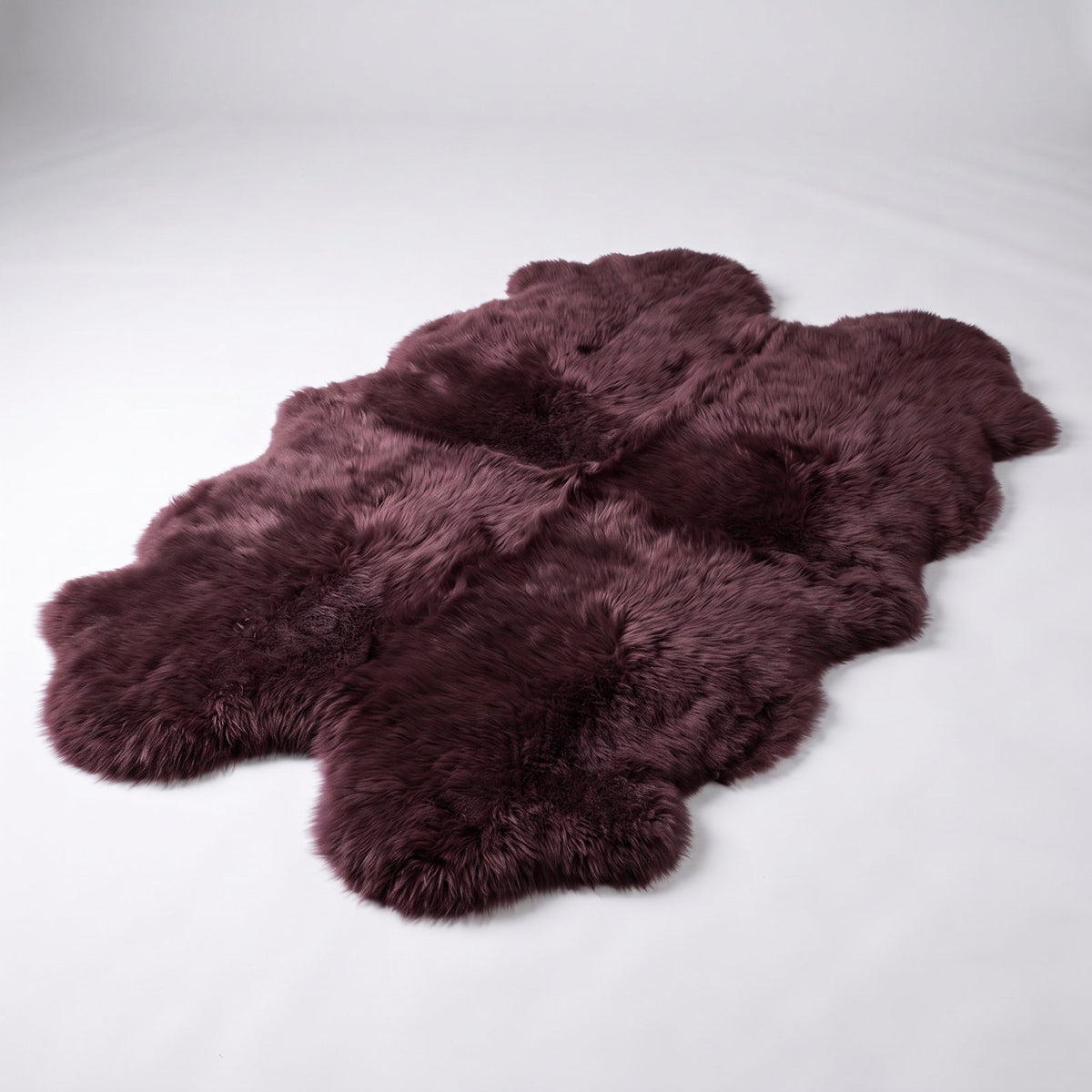 Aubergine quad New Zealand sheepskin rug, four deep plum pelts stitched together, studio shot