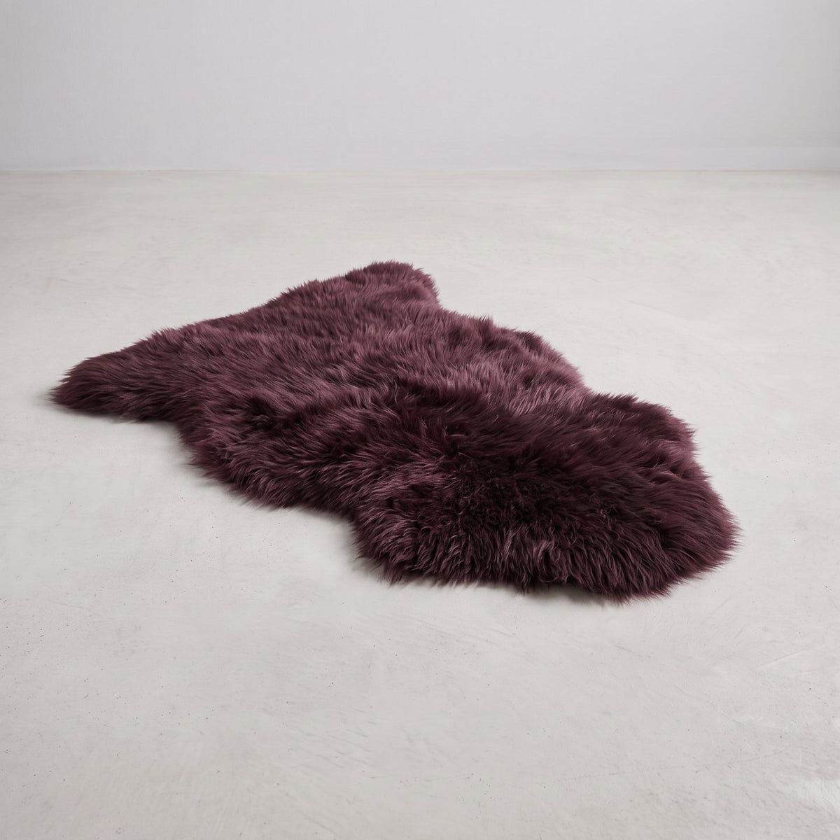 Aubergine single sheepskin rug laid on a pale floor