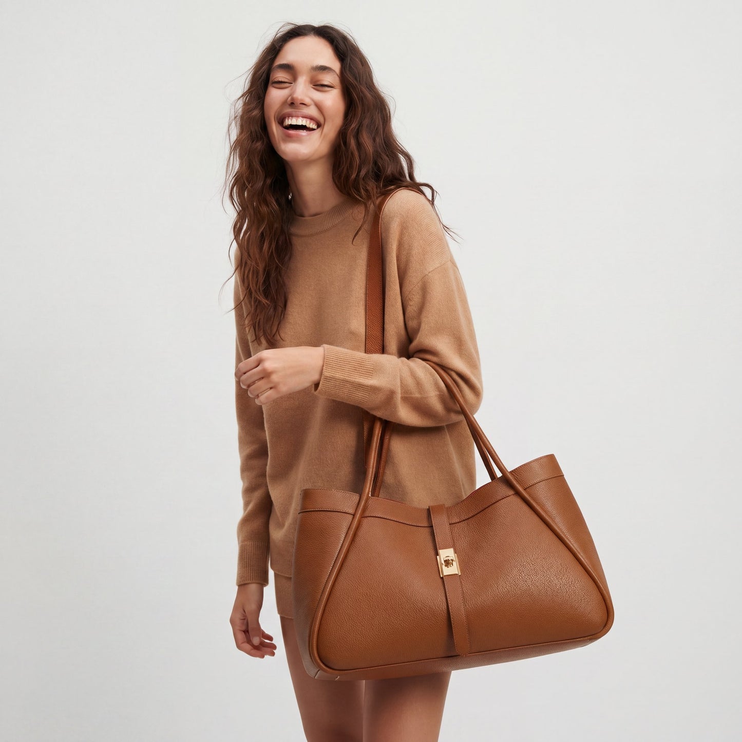 Model carrying the Dark Tan Bianca Large Leather Handbag by Clemés by its top handle, studio shot