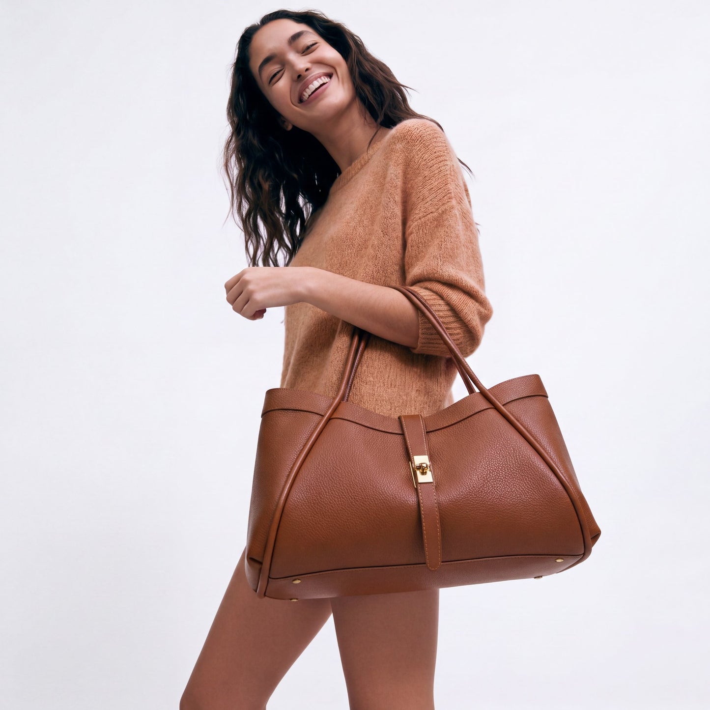 Model carrying the Dark Tan Bianca Large Leather Handbag by Clemés from the crook of her elbow, studio shot