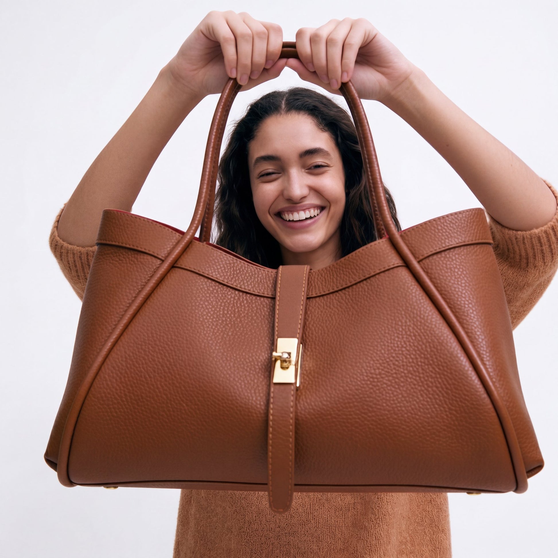 Close-up of the Dark Tan Bianca Large Leather Handbag by Clemés held up in both hands, studio detail shot