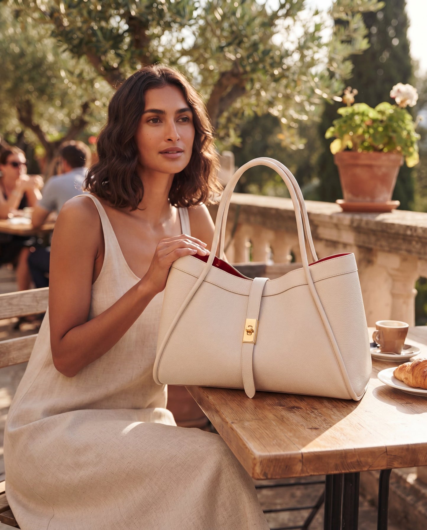 Woman with the Ivory Bianca Large Leather Handbag by Clemés at a sunlit café terrace
