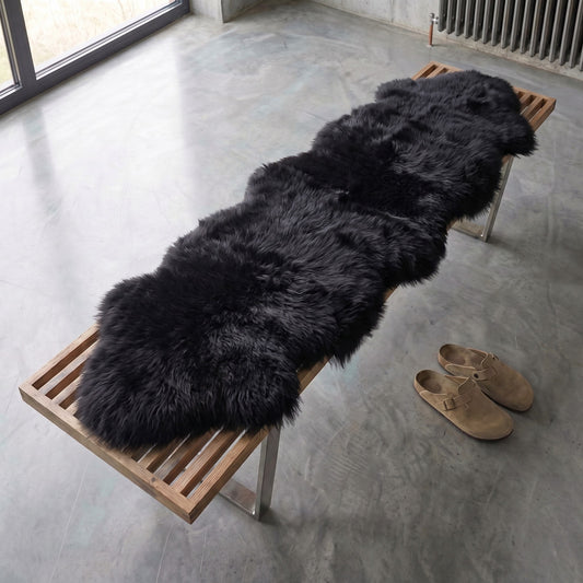 Black double New Zealand sheepskin rug and throw on a wooden bench