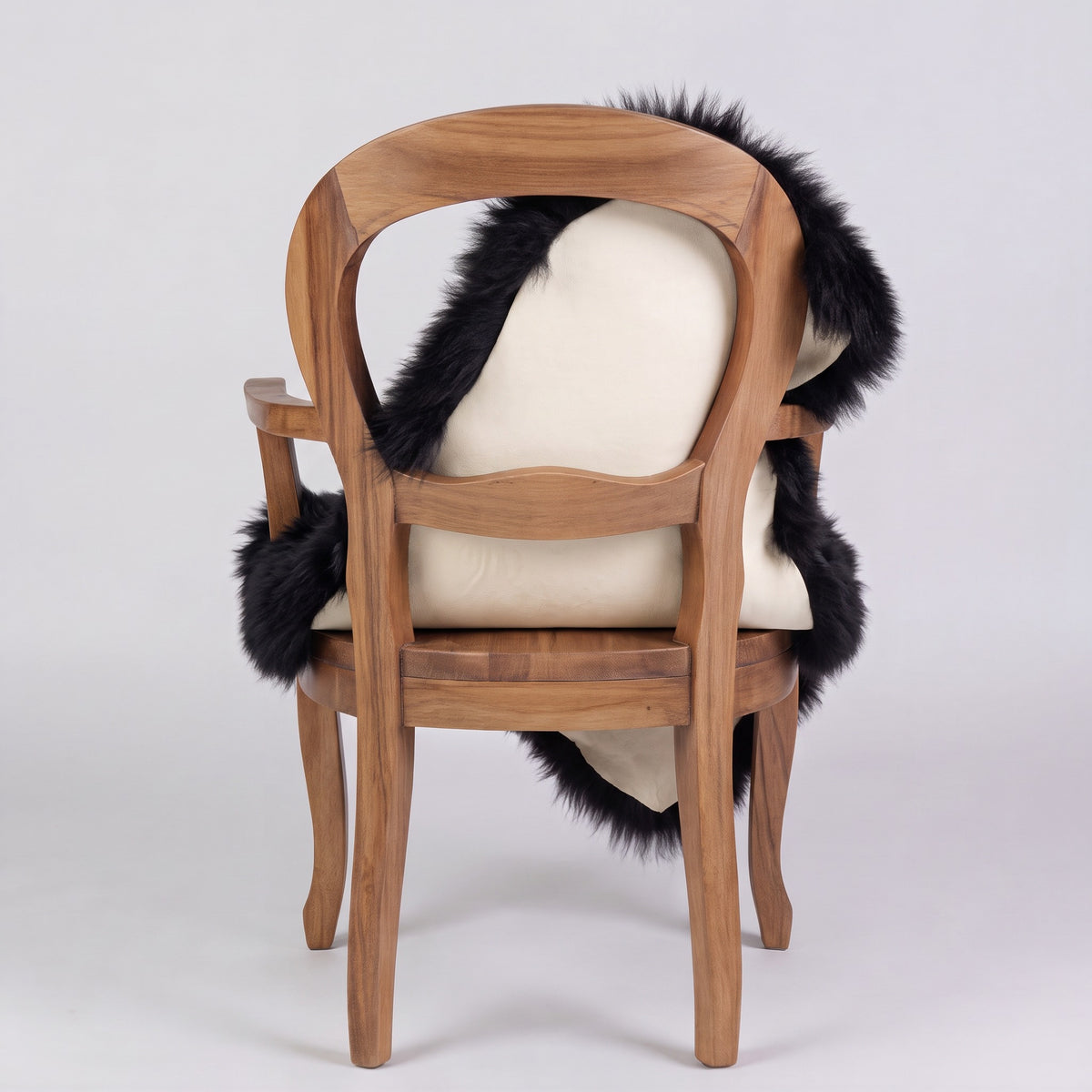 Black sheepskin rug over the back of a chair showing the cream suede underside