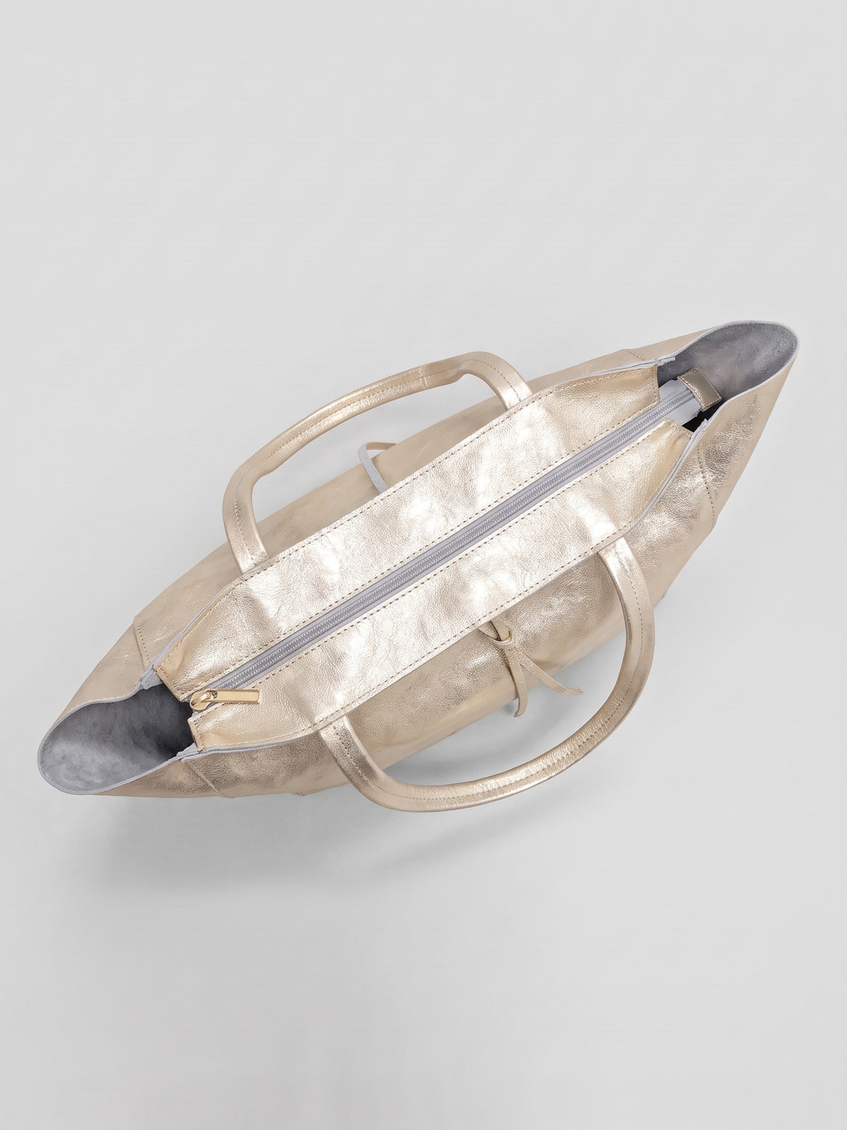 Carlotta oversized leather tote by Clemés in Champagne Gold metallic leather, top-down view of the closed top zip and handles