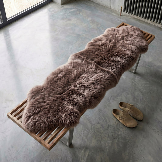 Taupe double sheepskin rug laid on a wooden slatted bench on a polished concrete floor