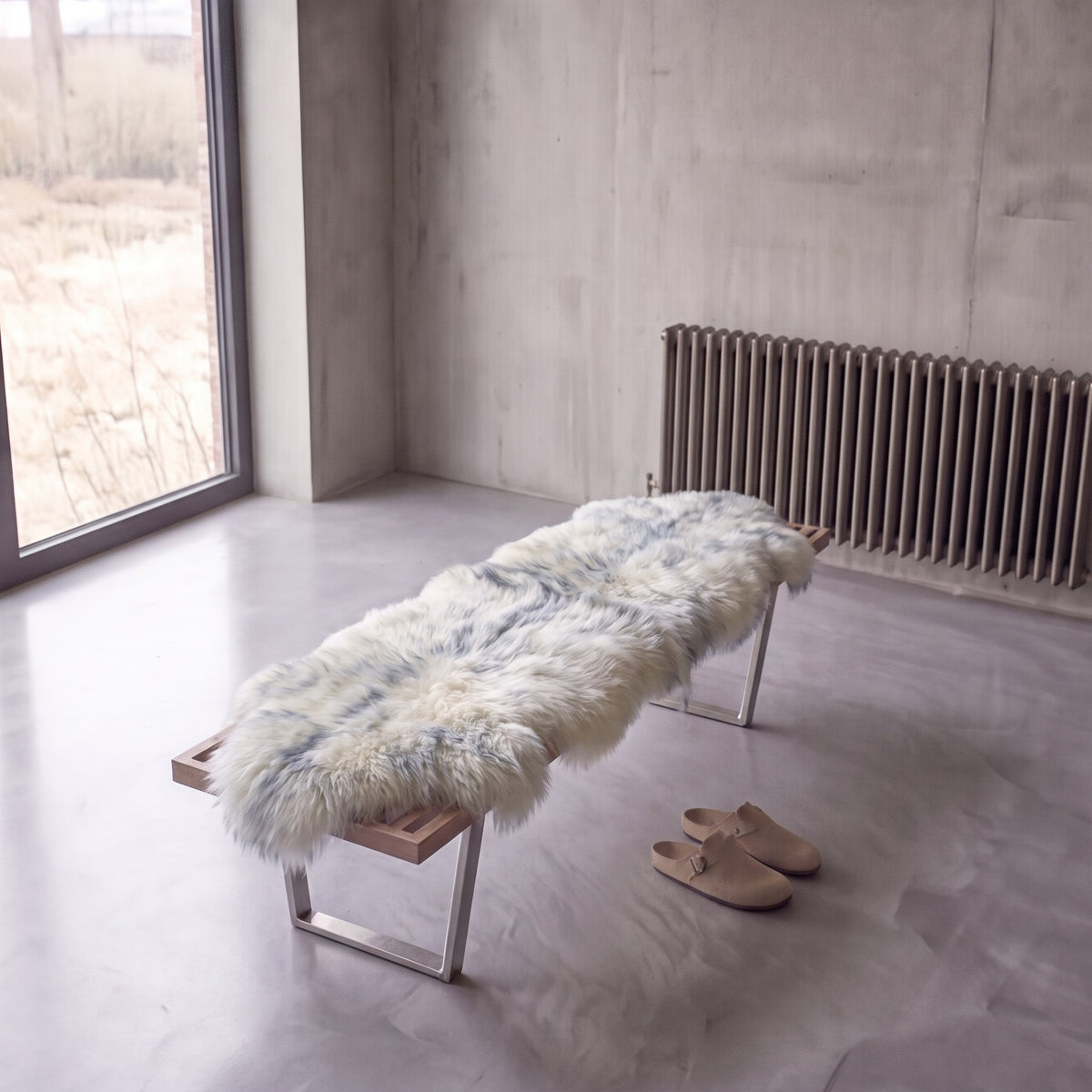 Grey Mist double New Zealand sheepskin rug and throw laid on a bench in a minimalist room