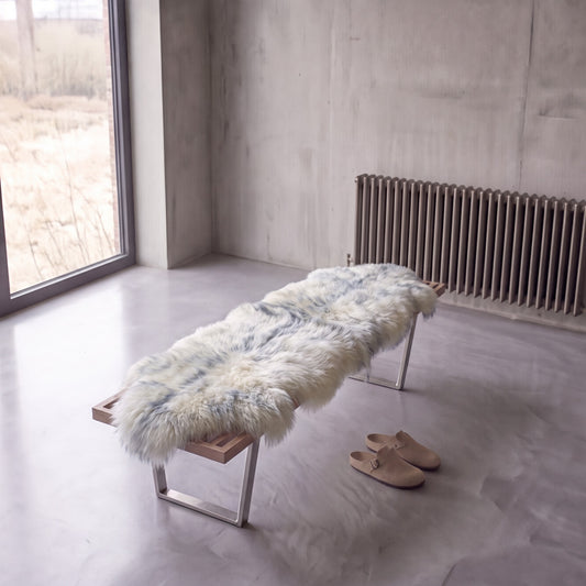 Grey Mist double New Zealand sheepskin rug and throw laid on a bench in a minimalist room