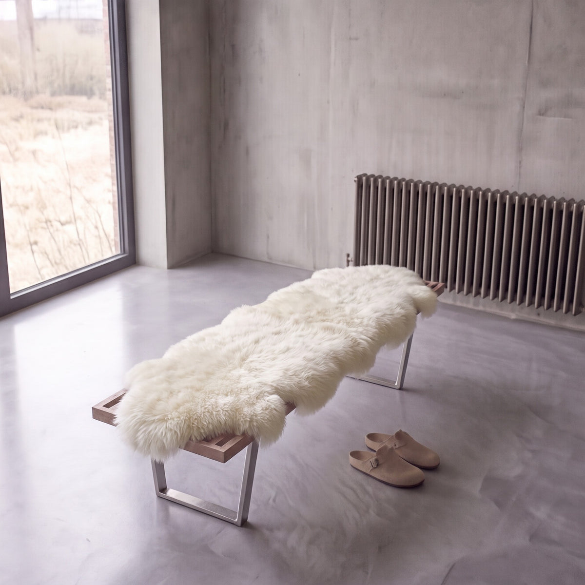 Ivory double New Zealand sheepskin rug and throw laid on a bench in a minimalist room