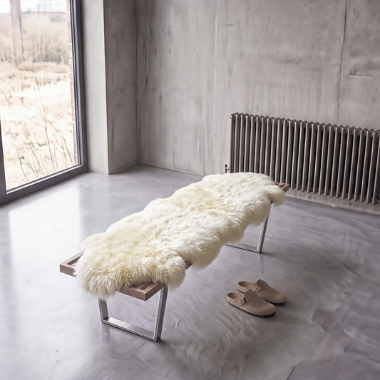 Ivory double New Zealand sheepskin rug and throw laid on a bench in a minimalist room