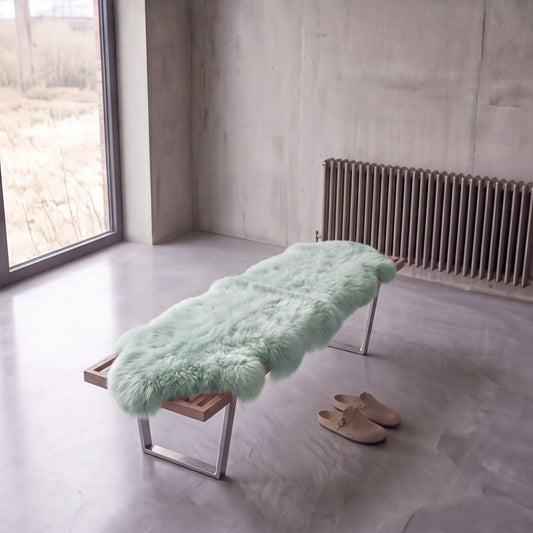 Sage double New Zealand sheepskin rug and throw laid on a bench in a minimalist room