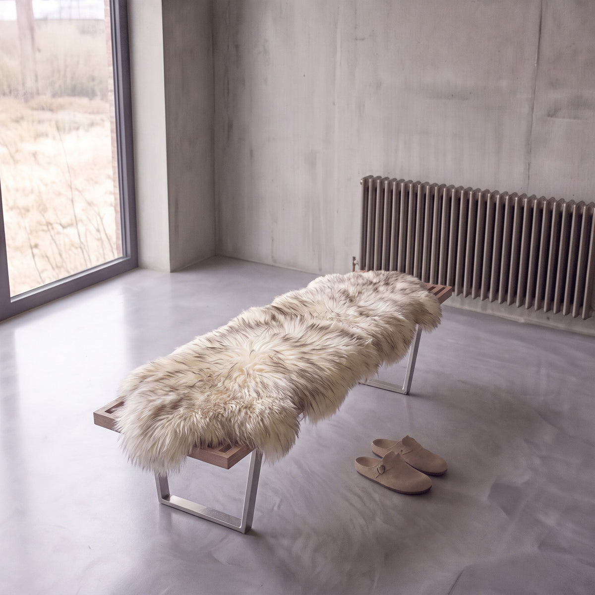 Wolf Tip double New Zealand sheepskin rug and throw laid on a bench in a minimalist room